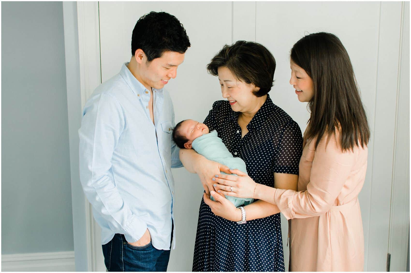 best newborn photography NYC with parents with the baby and grandmother wearing neutral color clothing 