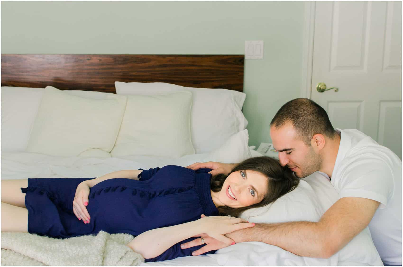 NYC maternity photography with husband kissing his pregnant wife in bed