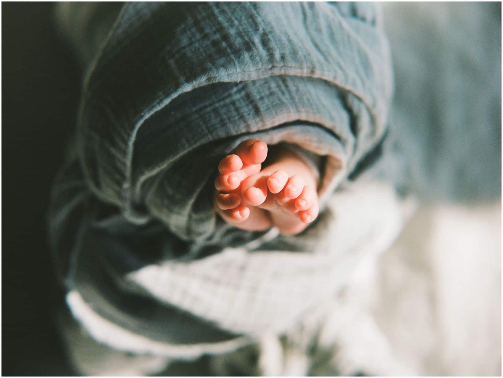 Newborn portrait of a closeup of baby feet wrapped in a blue blanket in Hoboken home
