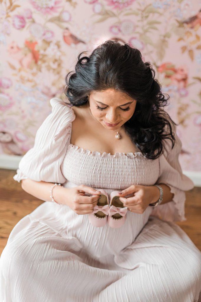 Overhead view of pregnant woman holding tiny pink baby shoes