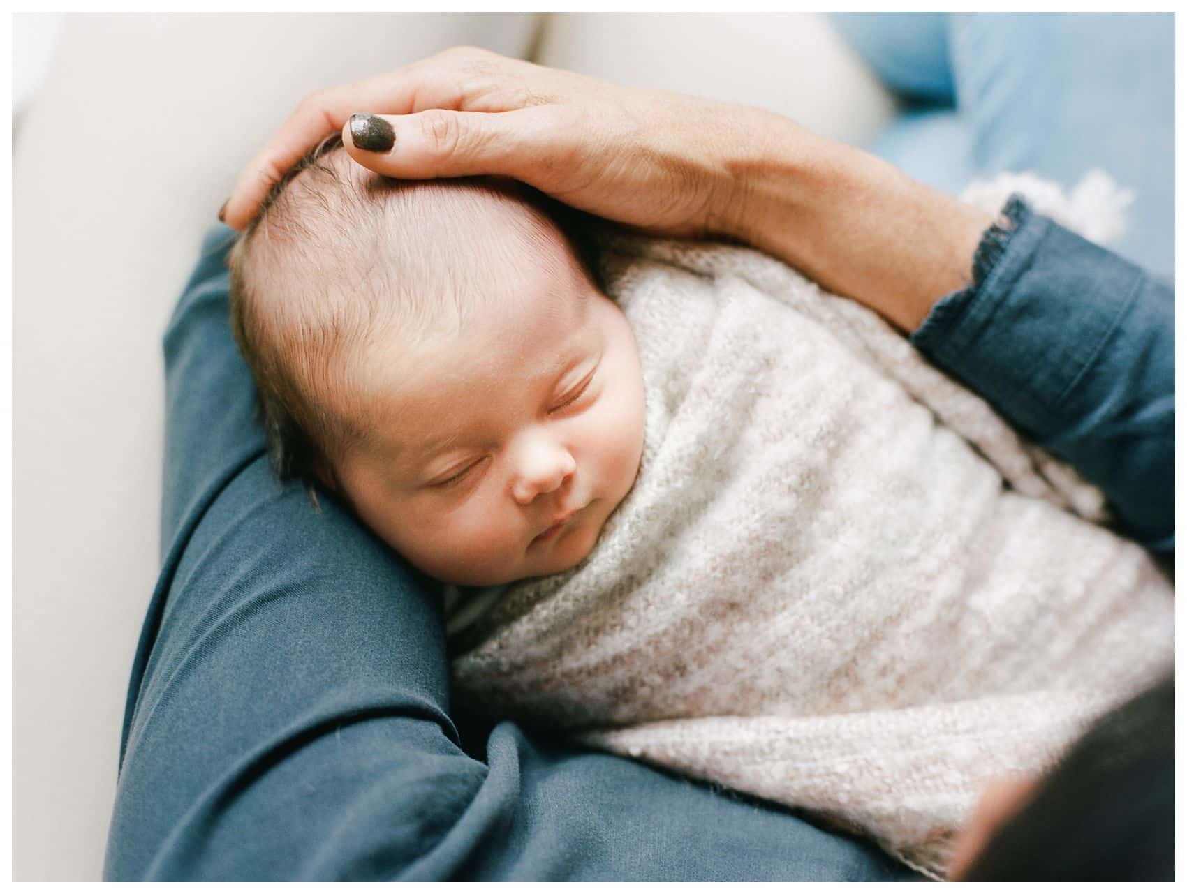 a grandmother is enjoying best Mother's day gift of a personal portrait holding newborn baby grand baby in her arms
