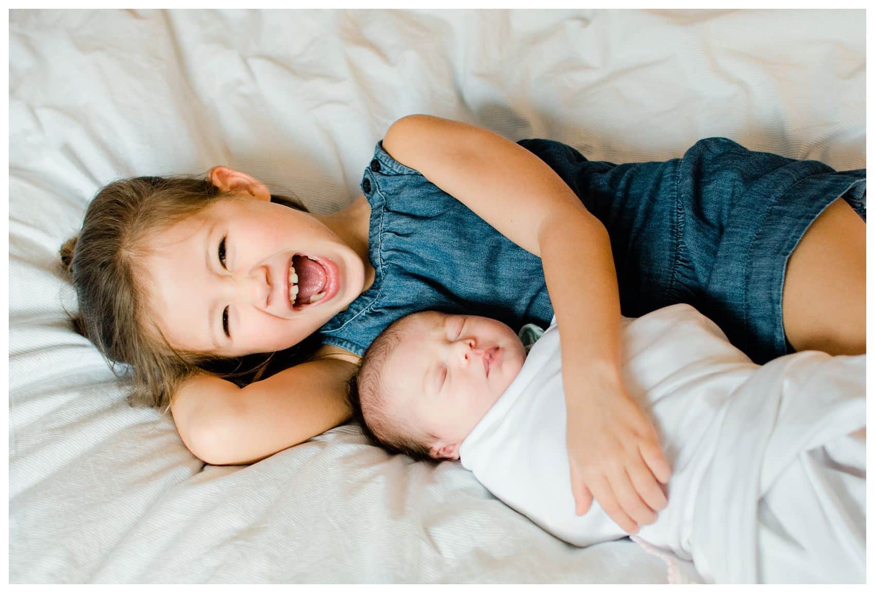 best gift idea for a mother is newborn portraits of your laughing kids on a white bed 
