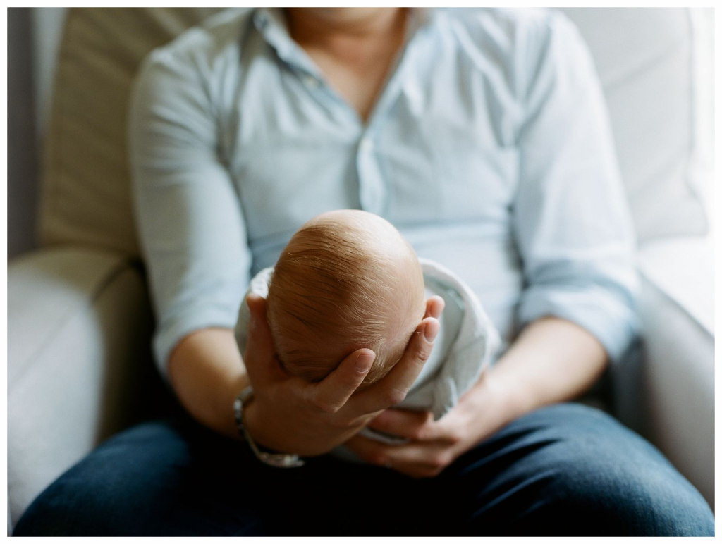 newborn baby boy nestled in dad's arms during in-home lifestyle session NJ
