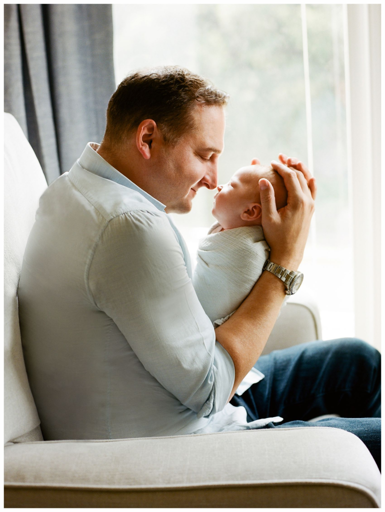 dad holding newborn baby during in-home lifestyle session NYC and NJ" — add NYC here
