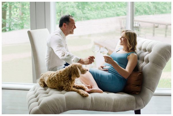 Maternity photography in Montclair, NJ capturing a pregnant couple raising a toast with their dog by their side, celebrating their journey to parenthood