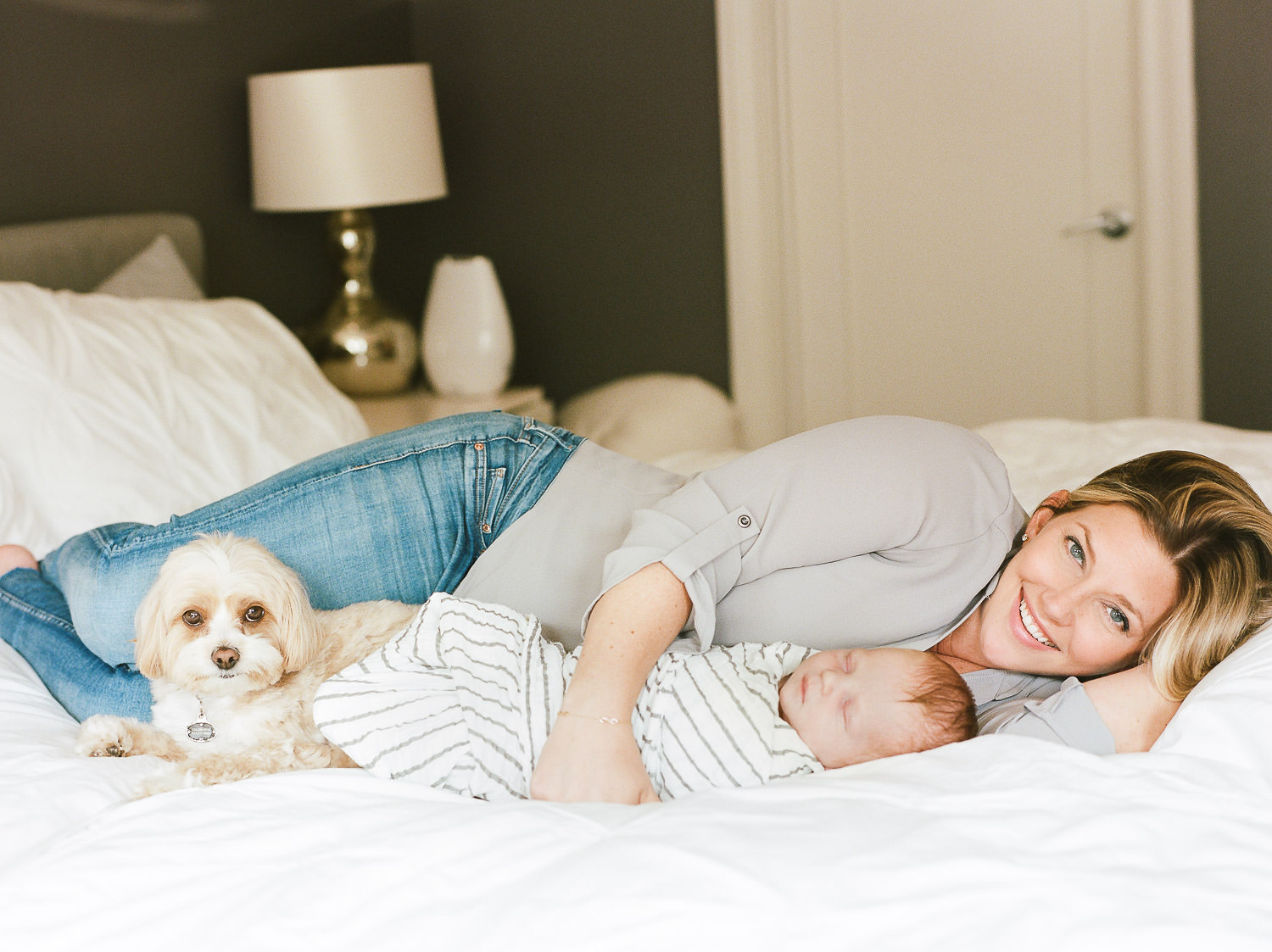 Mom lying in bed with her baby and dog during a newborn session in New Jersey