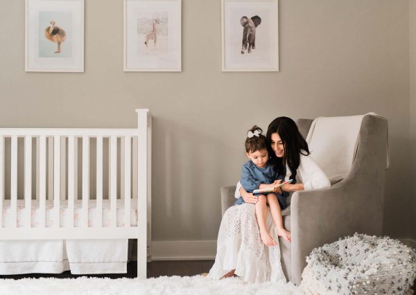 Best family photography in Upper West Side, NYC, capturing a mother and daughter reading together in a bright white bedroom