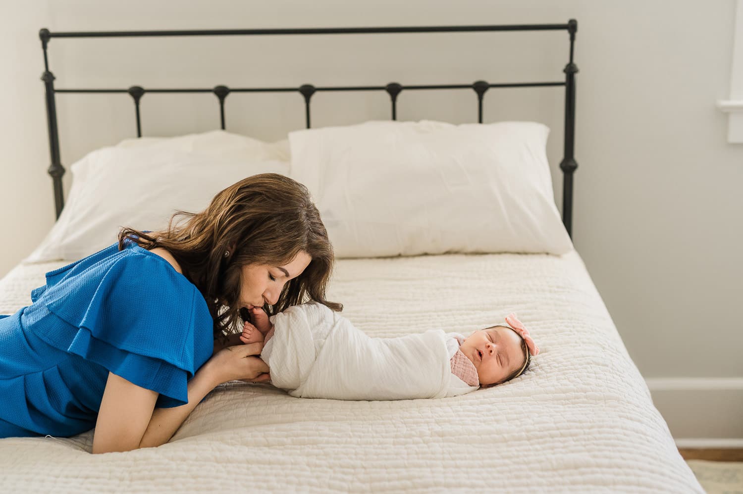 mom kissing her baby girl toes on the white bed in the Manhattan home