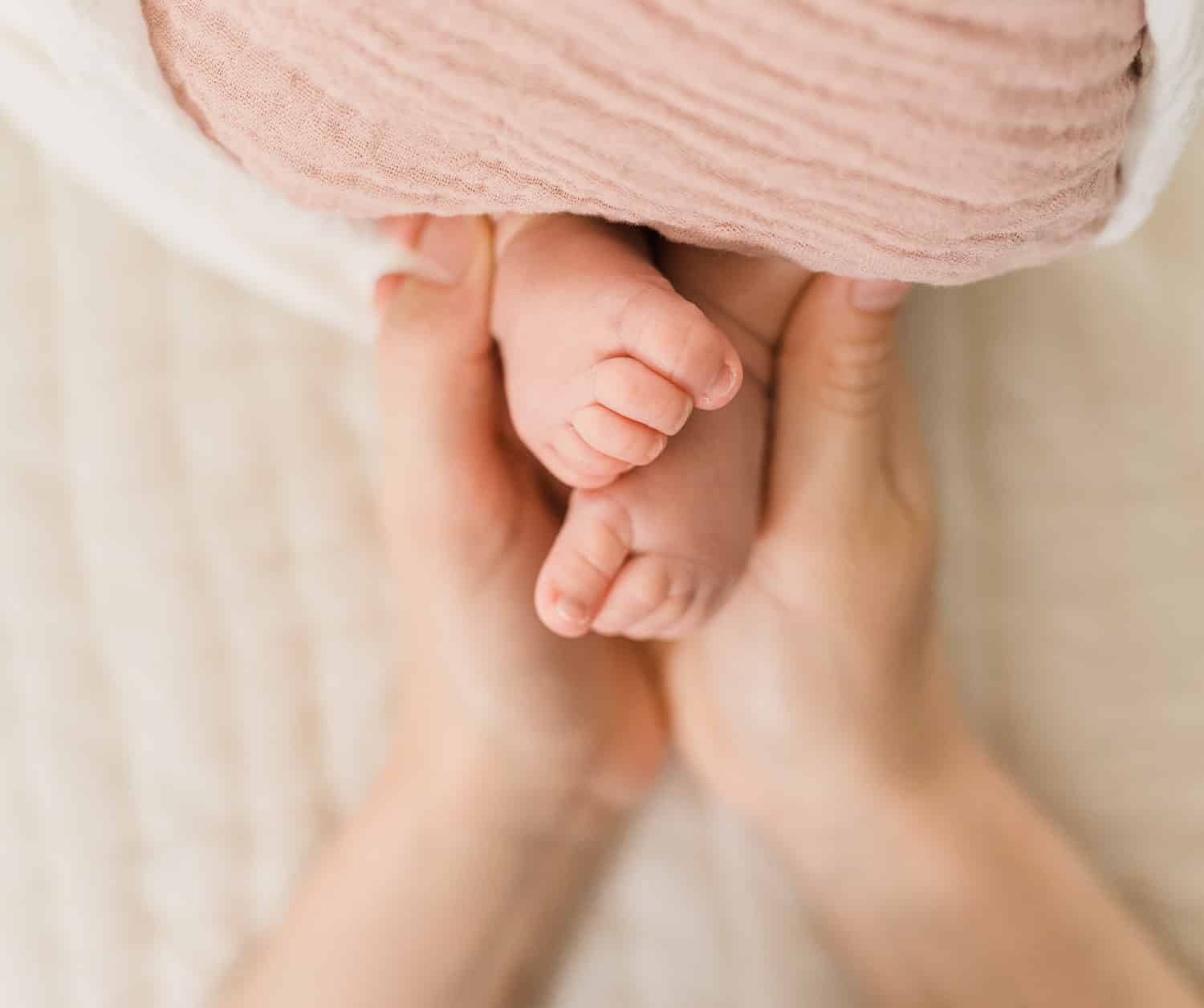 A close up of mom holding baby toes at Upper East Side during in-home newborn photo session
