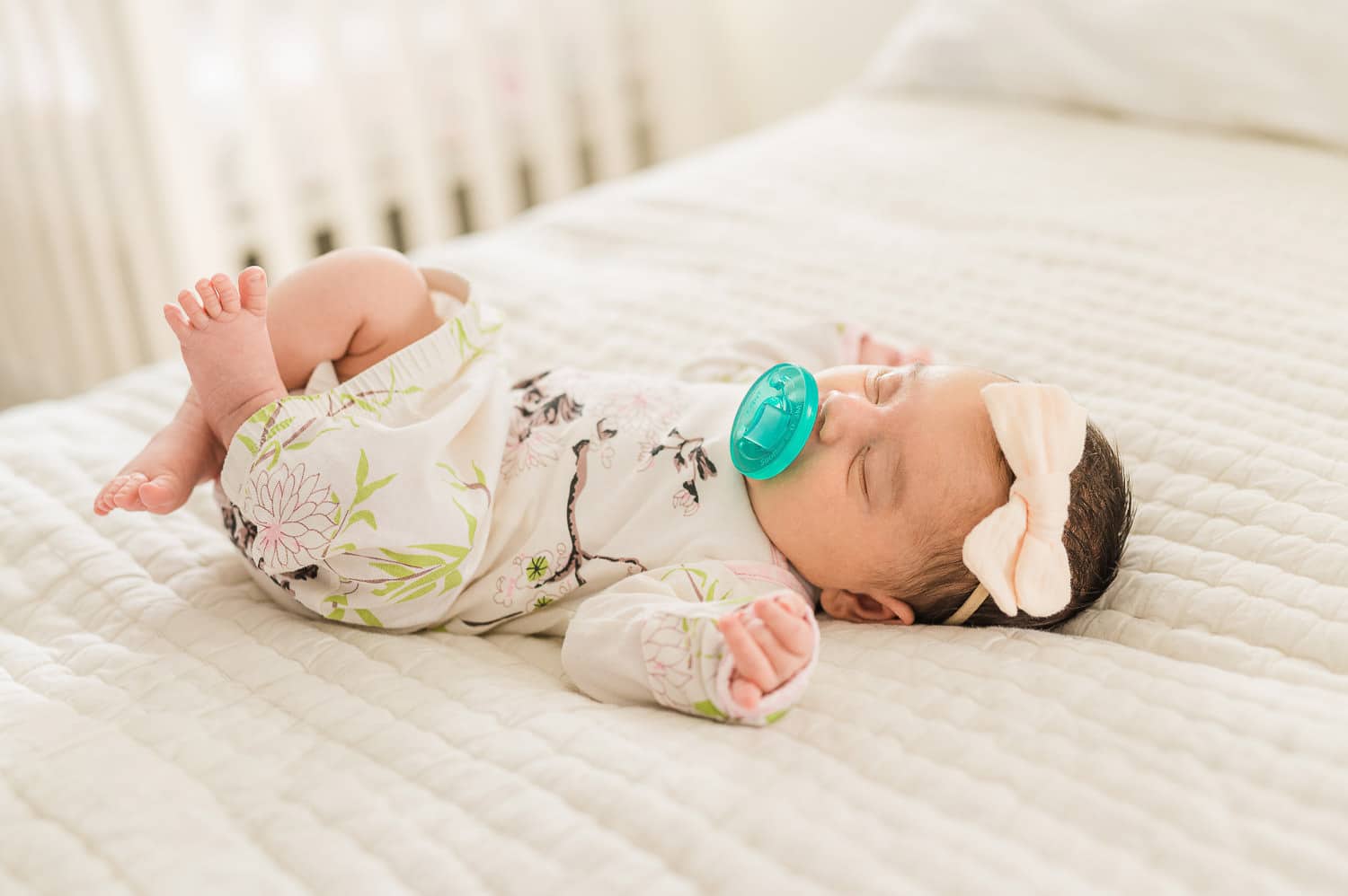 baby curled up with a hospital pacifier during newborn photography session