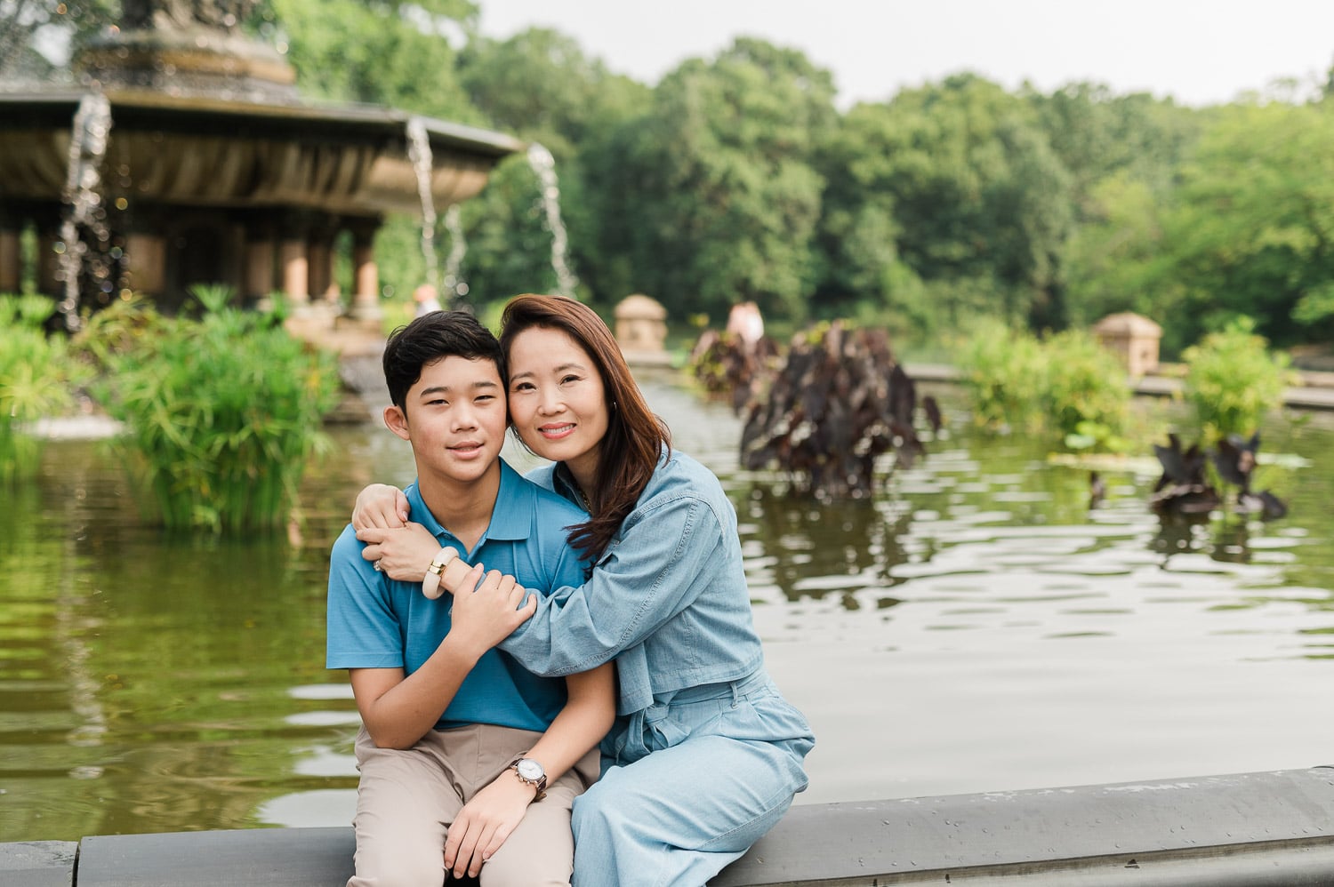 Natural family embrace with mom and her son by Bethesda Plaza fountain captured during Central Park family photography