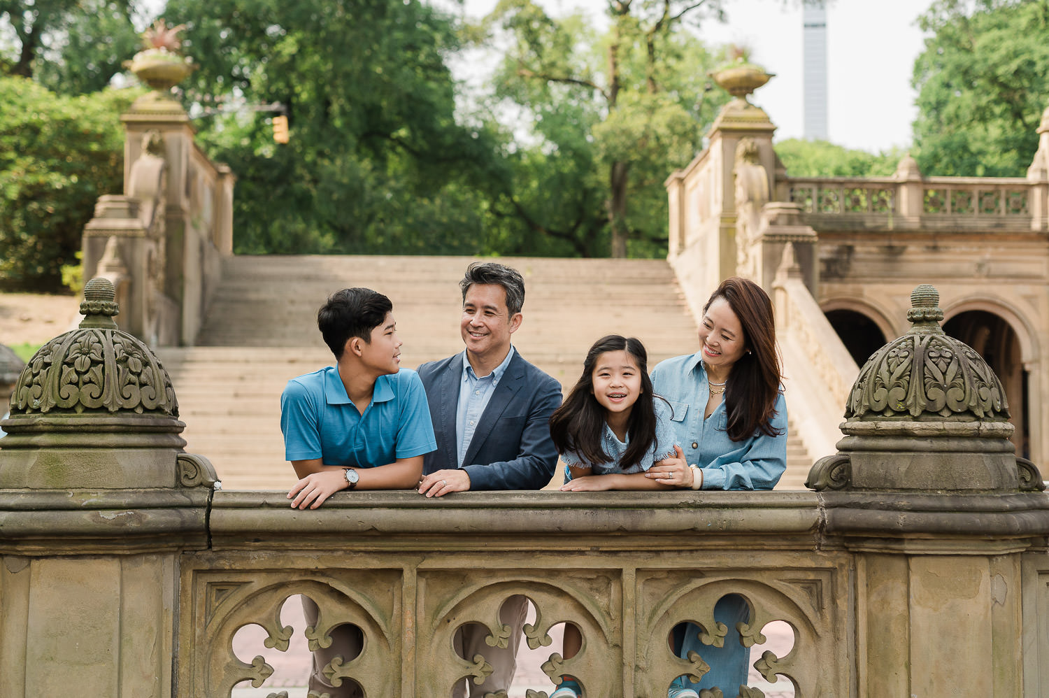 Fun Manhattan family of four by the New York CIty architecture and greenery of Bethesda Fountain