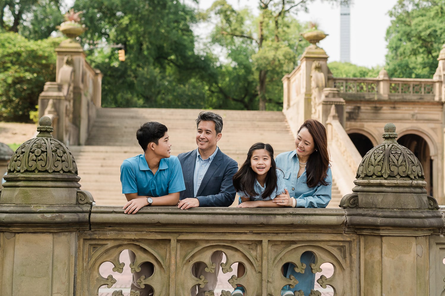 Fun Manhattan family of four posing for professional photos above Bethesda Terrace arches in Central Park