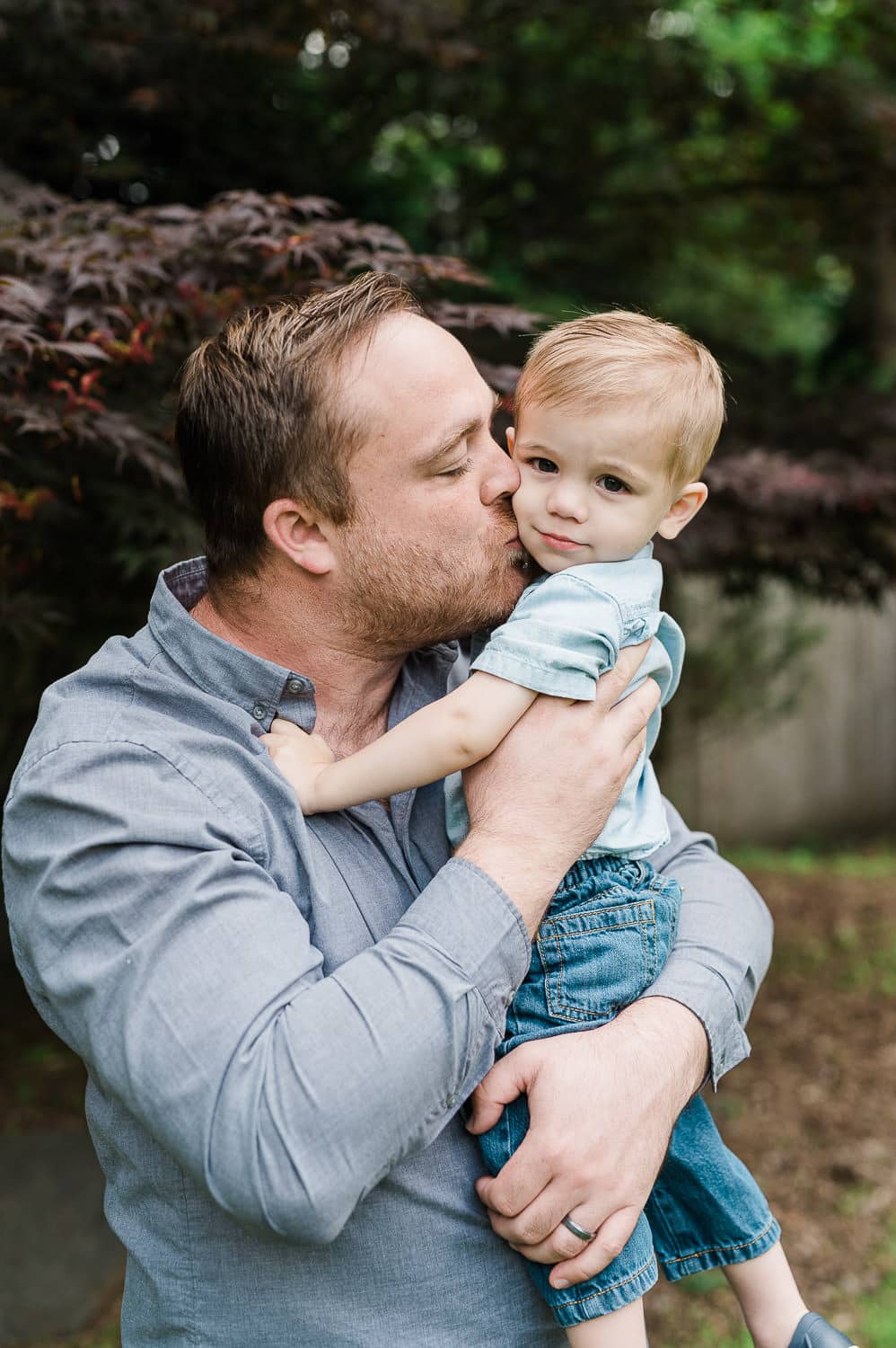 father kissing his 2 years old son in the backyard of their Summit, NJ family home