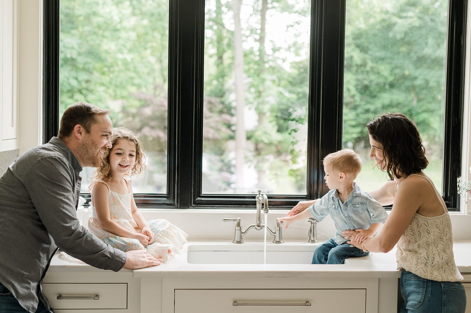 Family of four smiling together by kitchen window, Summit, NJ family photography