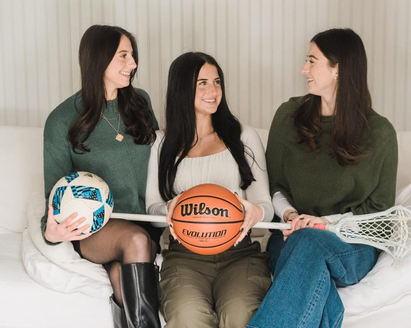 Three sisters laughing and holding soccer ball, basketball and lacrosse stick during senior portrait session in Bergen County NJ — senior portrait photographer Miriam Dubinsky