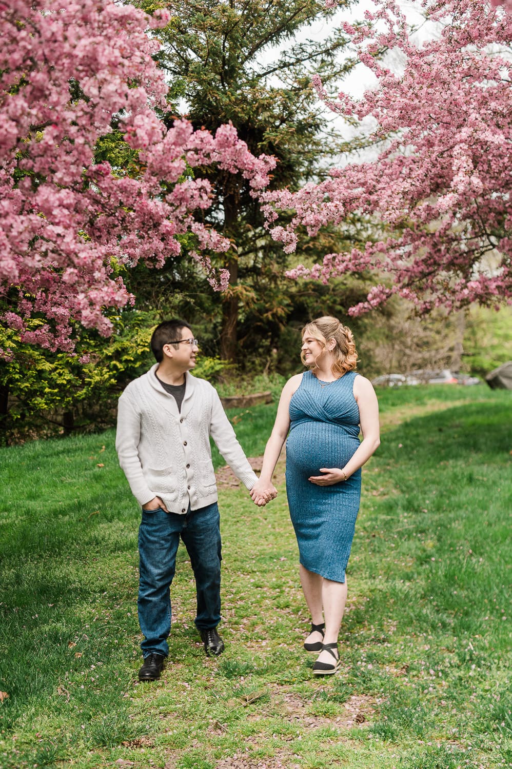 Maternity session in Morristown NJ with couple standing under cherry blossom trees in spring