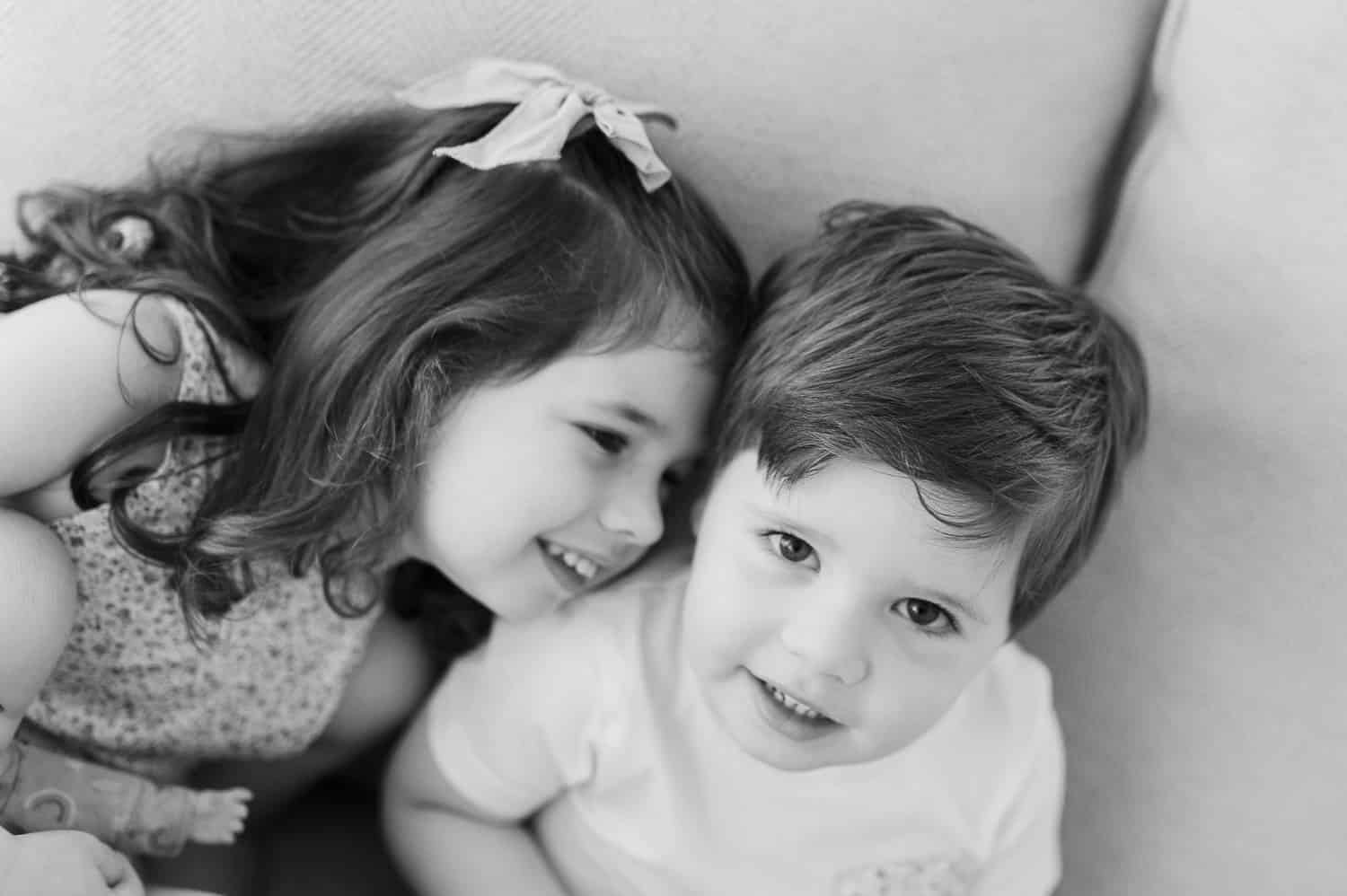 Black and white photo of older sister and brother cuddling together — sibling newborn session, Bergen County NJ