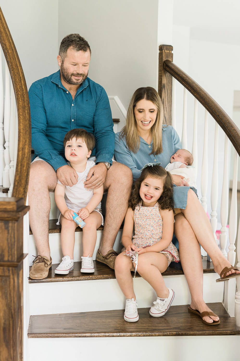 Family of five on a wooden staircase at home — lifestyle newborn photographer Miriam Dubinsky