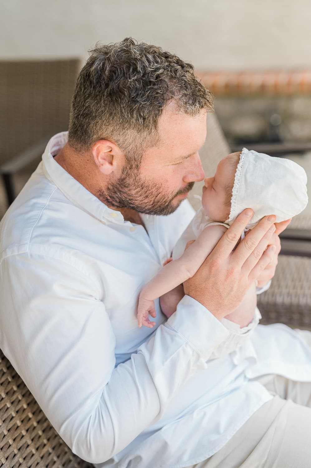 Father holding newborn baby nose to nose on outdoor patio — in-home newborn session with Miriam Dubinsky