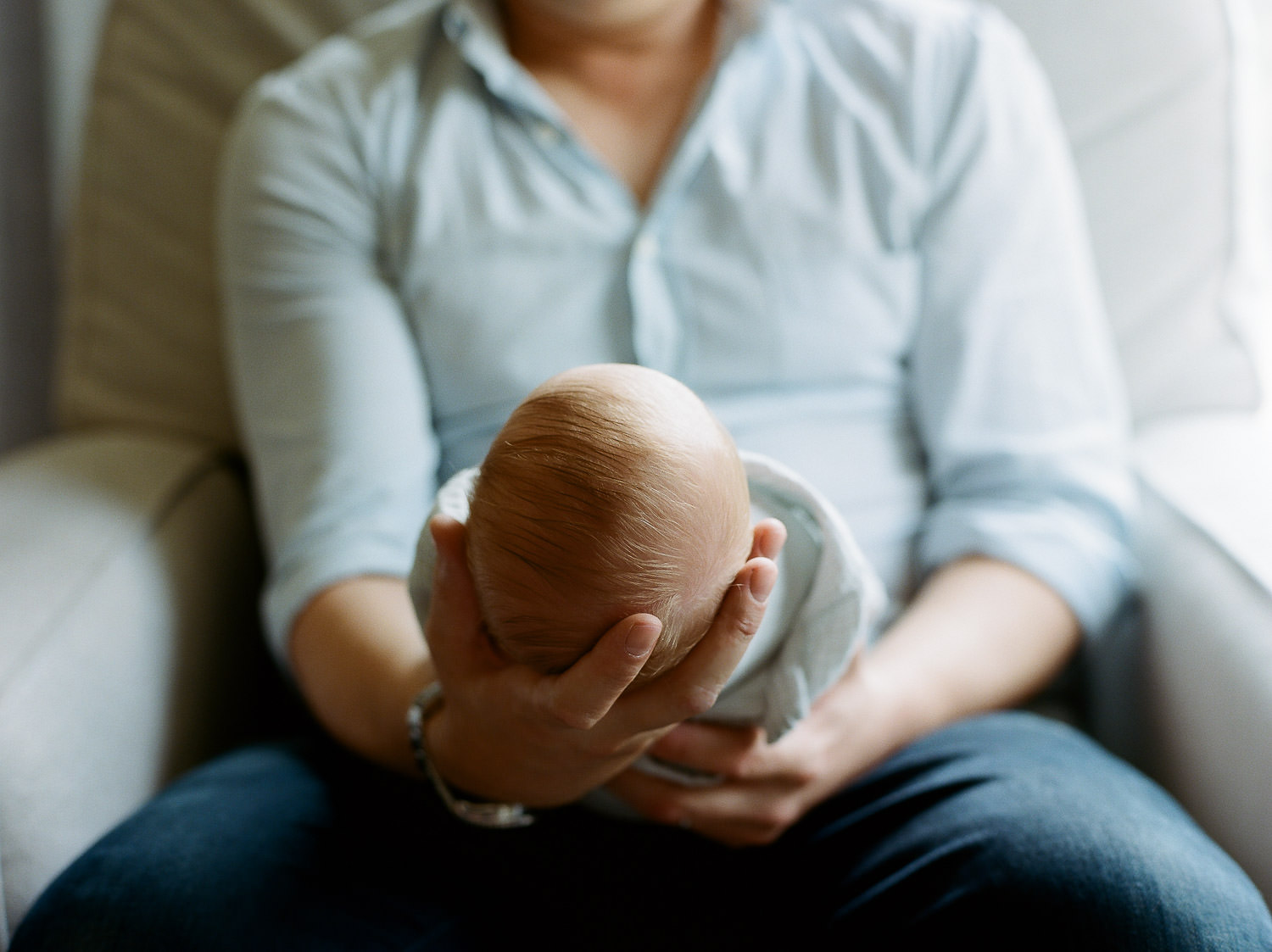 newborn baby boy nestled in dad's arms during in-home lifestyle session NJ