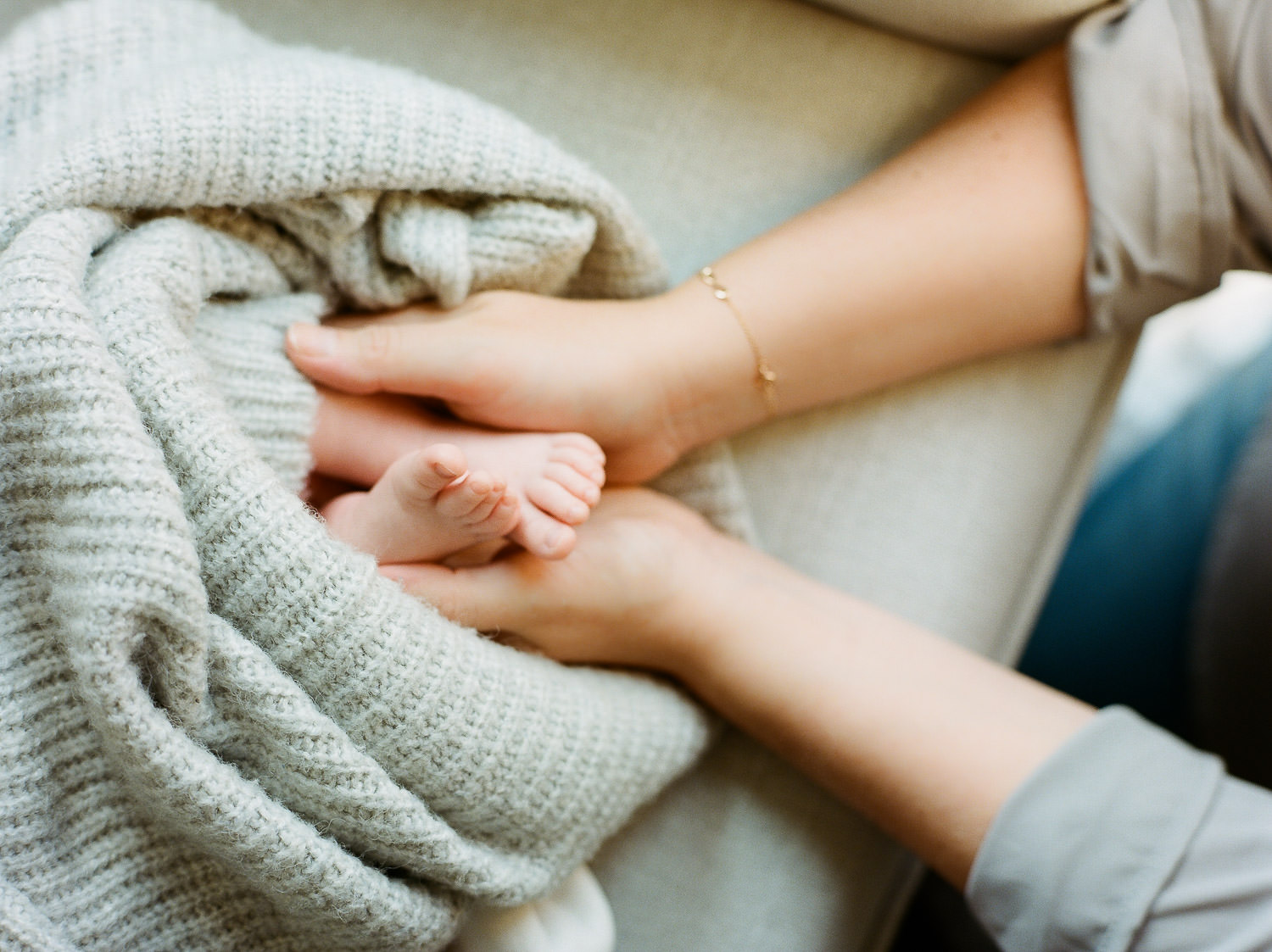 mom holding newborn baby toes during in-home lifestyle session NJ