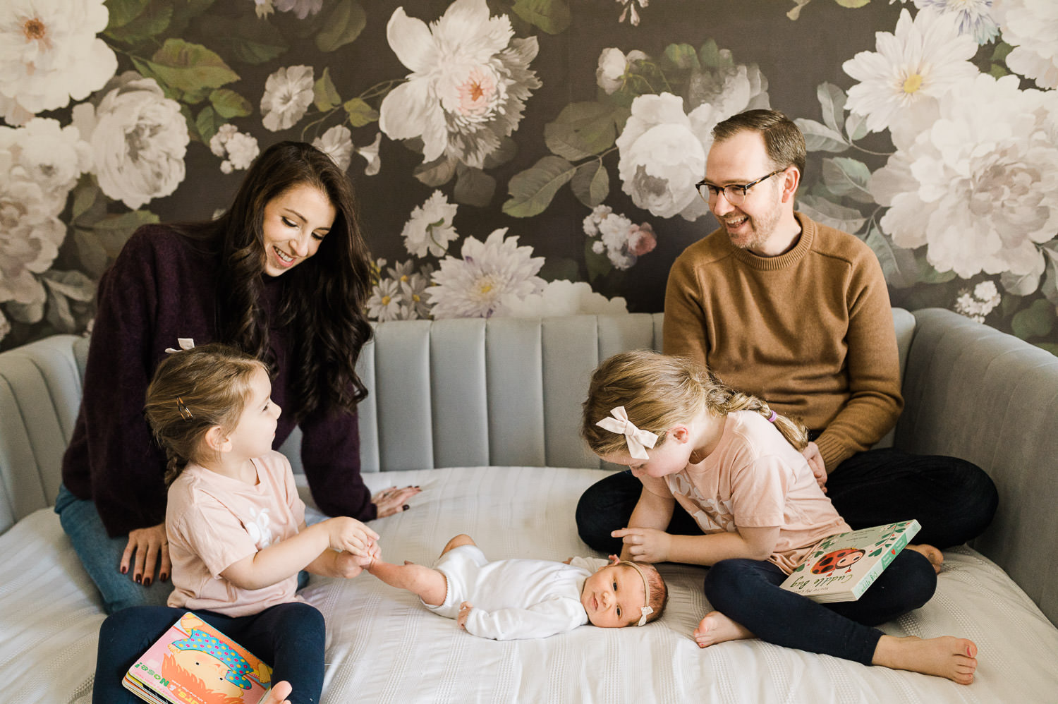 Newborn photos with older siblings in NJ  where mom and dad watching their two little girls adore their newborn sister