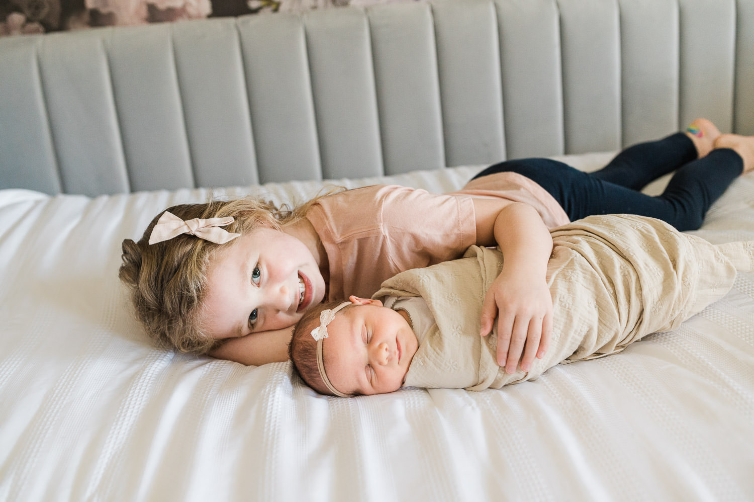 Older sister cuddling  with her sleeping baby sister during newborn photos with older siblings in NJ