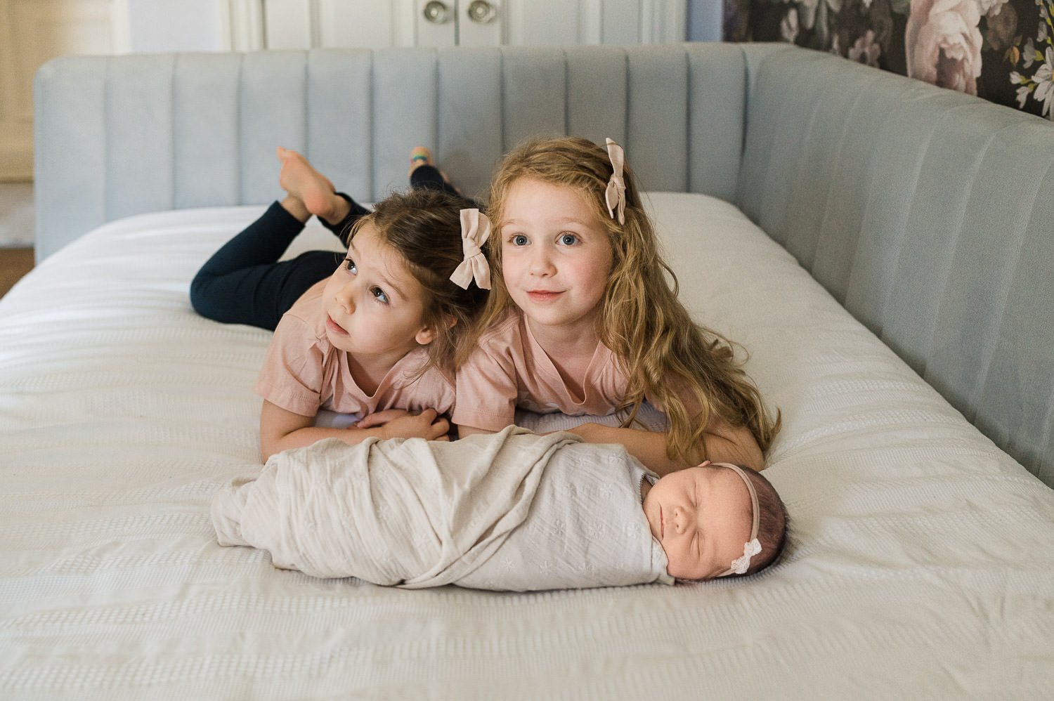 newborn photos with older siblings NYC — baby lying on blanket with older sibling and cat during in-home session