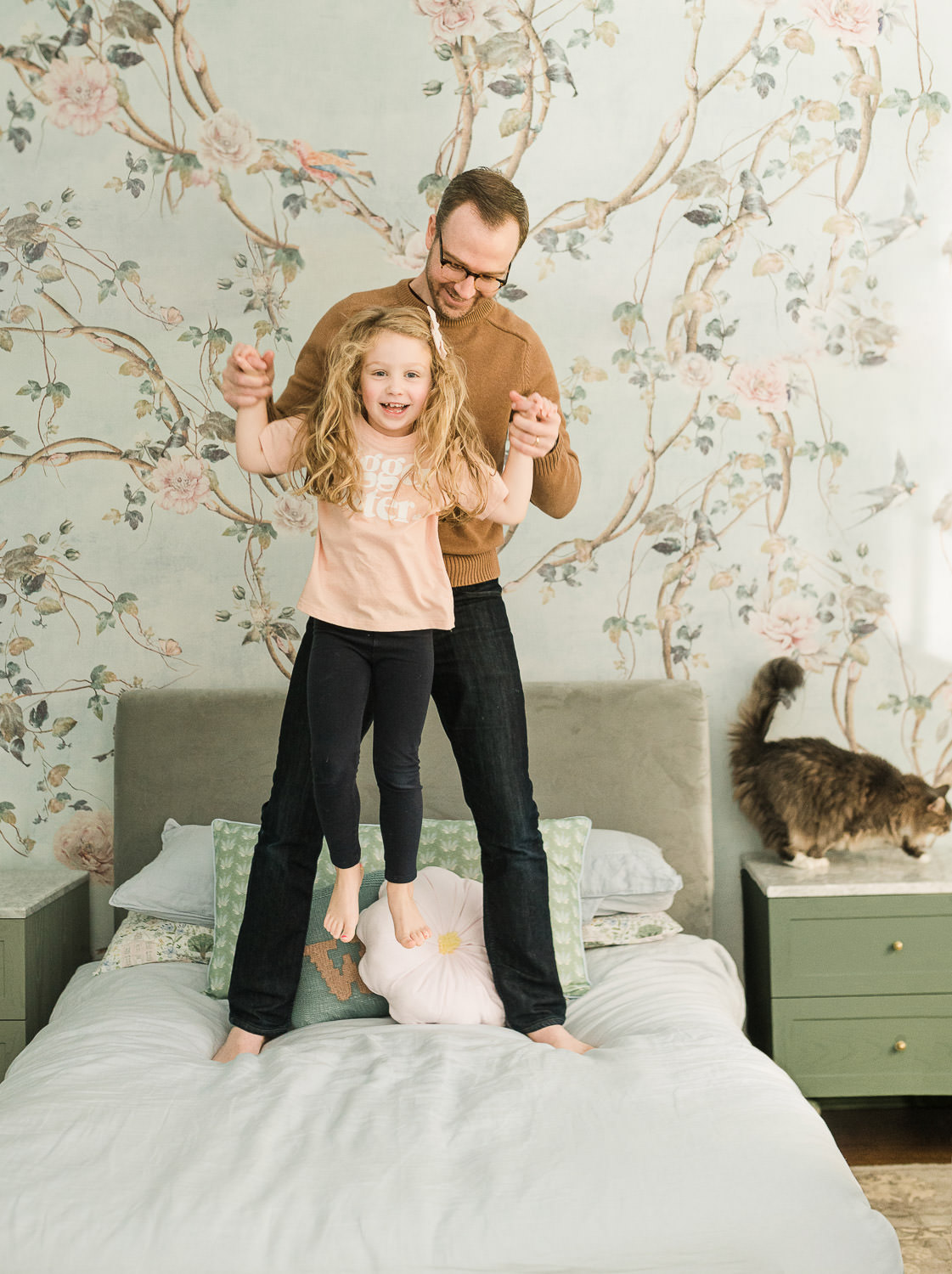 father and older daughter jumping on bed during in-home sibling newborn session NJ