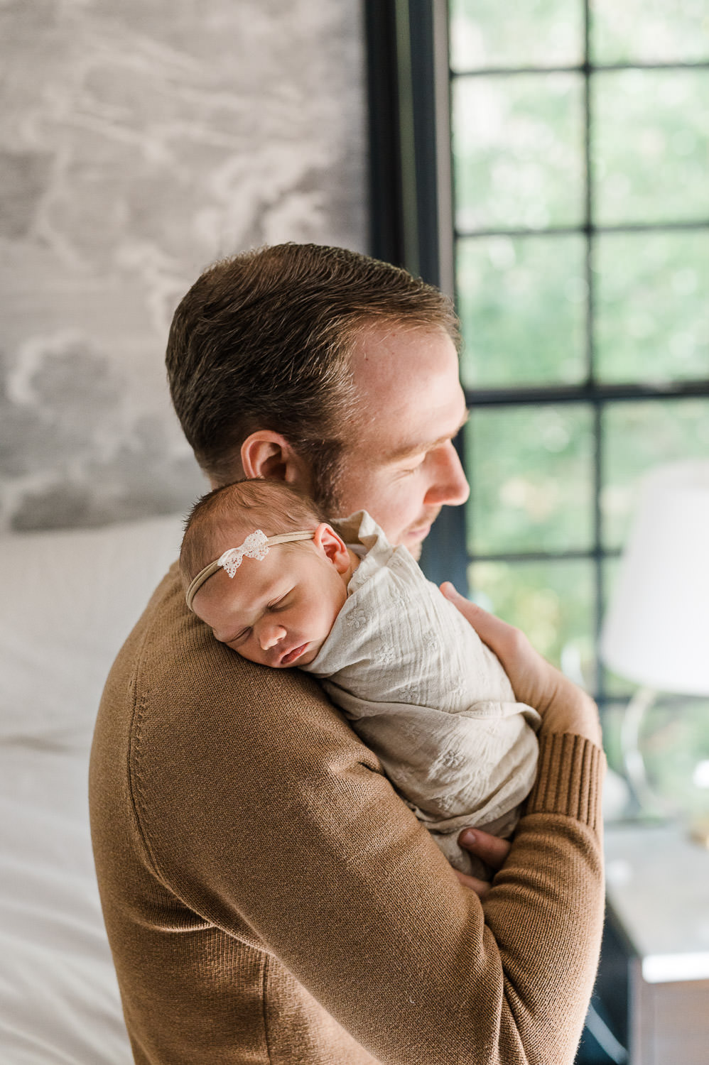 new father is holding gently his new baby girl in their bedroom photographed by Miriam Dubinsky Photography